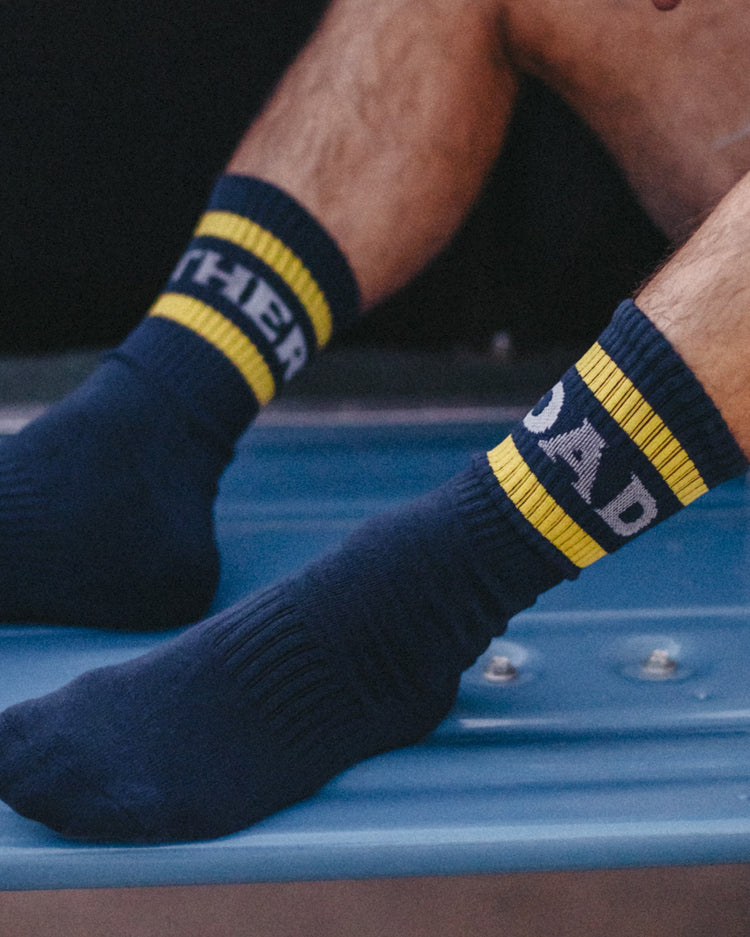 Close-up of navy Mother Road socks with yellow stripes on a blue truck bed